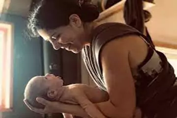 Mother breastfeeding her newborn baby at home
