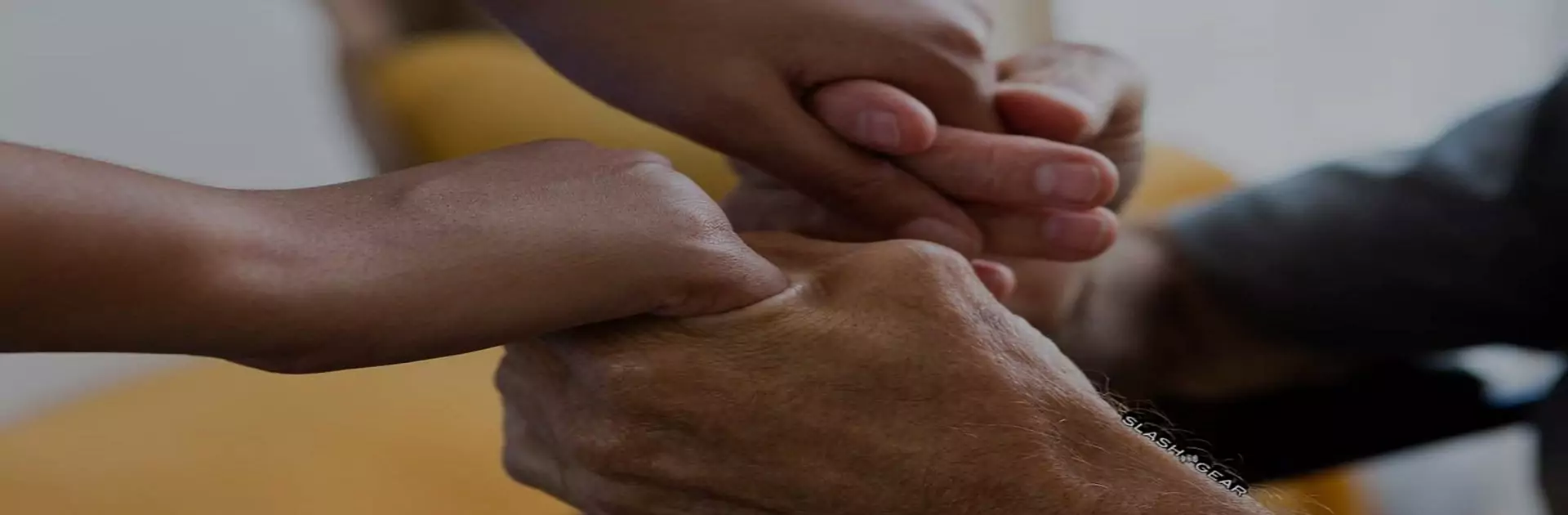 Caregiver holding the hands of an elderly patient at home