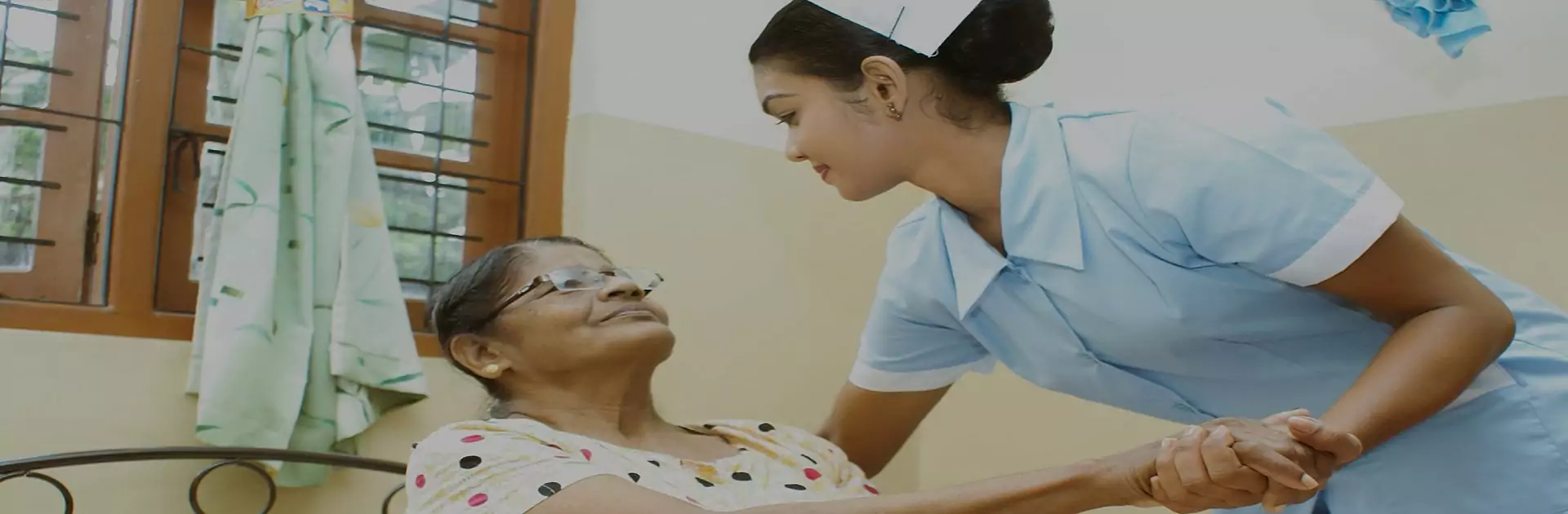 Nurse checking on an elderly woman resting in bed at home
